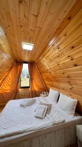 Cama grande en habitación con techo de madera en Liniștea Muntilor en Cîrţişoara