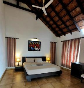 a bedroom with a large bed and two windows at Rain Clouds Wayanad Forest Retreat - The Best Couple Friendly Private Cottages with Bathtub in Wayanad