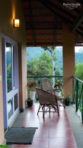 two chairs sitting on a porch with a view at Rain Clouds Wayanad Forest Retreat - The Best Couple Friendly Private Cottages with Bathtub in Wayanad