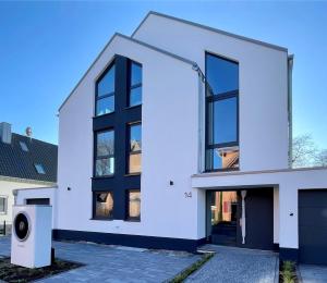 ein weißes Haus mit schwarzen Fenstern in der Unterkunft Luxuswohnung 95qm in Waldrandlage zwischen Köln und Düsseldorf-Nähe Messe - Lanxessarena - Bayarena in Leverkusen