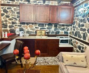 a kitchen with wooden cabinets and a stone wall at ΑΝΑΛΗΨΗ in Palaios Agios Athanasios