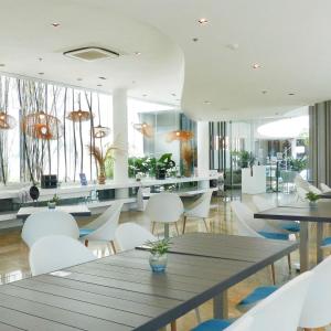 uma sala de jantar com mesas e cadeiras brancas em Lovely Room em Maribago