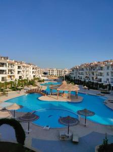 Riviera Resort Apartment - Pool view & Wifi في شرم الشيخ: مسبح كبير مع مظلات وبعض المباني
