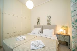 een witte slaapkamer met 2 bedden en handdoeken bij Rania Apartments Helmata in Khelmáta