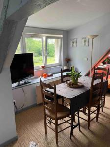 a dining room with a table with chairs and a television at Le Vieux Moulin Chamant Senlis 60300 in Chamant