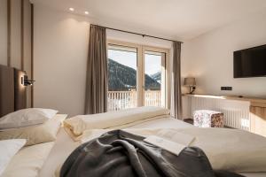 two beds in a hotel room with a window at Jagdhof PURE Mountain Appartements in Tux