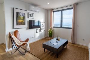 a living room with a table and a chair at Apartamentos do Mercado in Covilhã