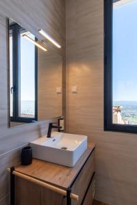 a bathroom with a white sink and two windows at Apartamentos do Mercado in Covilhã
