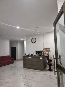 a lobby with a clock on the wall and a counter at Shivaji Inn Kaziranga in Kāziranga