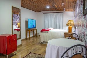um quarto com uma cama, uma televisão e uma mesa em Hotel Ascona em Campos do Jordão