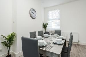 uma mesa de jantar com cadeiras e um relógio na parede em Hornsey Lodge - Anfield Apartments em Liverpool