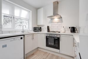 a white kitchen with a sink and a stove at Hornsey Lodge - Anfield Apartments in Liverpool