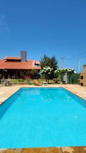 a large blue swimming pool in front of a house at Vila icarai in Caucaia