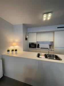 a kitchen with white cabinets and a sink at Vakantieappartement - Gratis garage - Topligging in Ostend