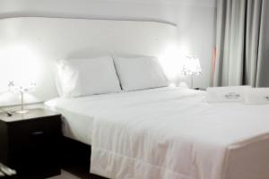 a bedroom with a white bed with two lamps at Hotel Venture in Chincha Alta