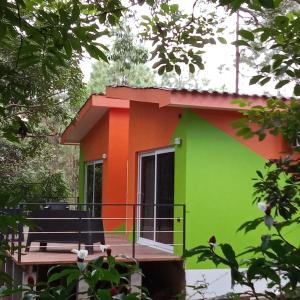 a green and orange house with a bench on a deck at Cabañas LuMa in Guanteque