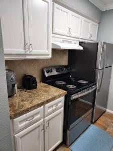 een keuken met een zwarte kachel en witte kasten bij Blue Shark *E19* @ Midtown Functional 1BR King Apartment in Houston