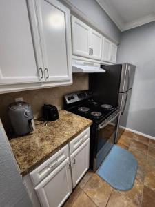 a small kitchen with a stove and white cabinets at Blue Shark *E19* @ Midtown Functional 1BR King Apartment in Houston