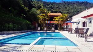 einen Pool mit Tischen und Stühlen neben einem Gebäude in der Unterkunft Hotel Vila Nova in Teresópolis