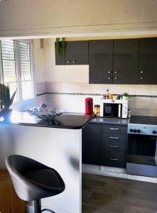 a kitchen with a counter and a chair in it at T2 Cosy autonome h24 Parking privé attenant TV 165cm Netflix wi-fi au Rez-de-chaussée in Alençon