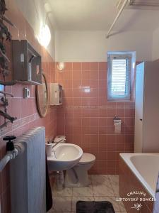 uma casa de banho rosa com um lavatório e um WC em Chalupa Liptovský domček em Liptovský Mikuláš
