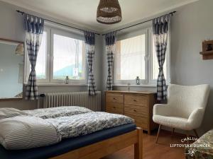 sypialnia z łóżkiem, krzesłem i oknami w obiekcie Chalupa Liptovský domček w Liptowskim Mikulaszu