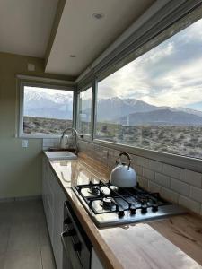 ポトレリージョスにあるVillamagna, casa en Potrerillosのキッチン(コンロ付)、山の景色を望む窓2つが備わります。
