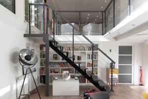a staircase in a living room with a book shelf at Spacious and quiet apartment with shared garden in Issy-les-Moulineaux