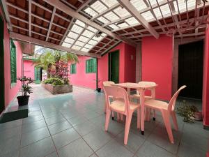 a table and chairs on a patio with pink walls at Suítes Casa Rosada in Ubatuba