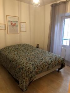 ein Schlafzimmer mit einem Bett mit einer Blumendecke in der Unterkunft Appartement BELLO , ruelle au cœur de ville, arrivée en autonomie in Lons-le-Saunier