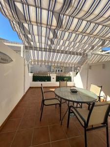 a patio with a table and chairs under a roof at apartamento torrequebrada in Benalmádena