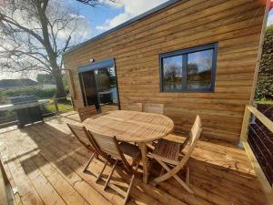 a wooden table and chairs on the deck of a cabin at Chalet les pieds dans l'eau la campagne à la ville in Saint-Doulchard