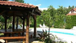 a wooden pavilion with a table and chairs next to a pool at Palatinus Apartmanok in Keszthely
