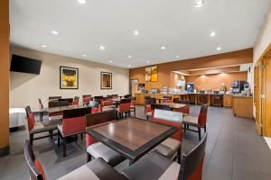 a dining room with tables and chairs and a kitchen at Comfort Suites Kansas City-Liberty in Liberty