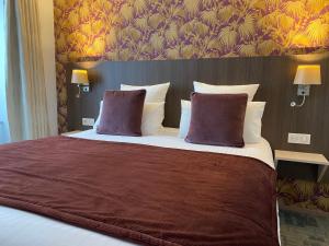 Cit'Hotel Hôtel de France et d'Europe في كونكارنو: غرفة نوم بسرير كبير مع وسادتين