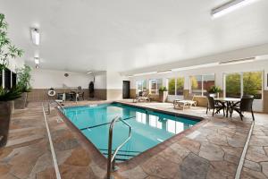 a swimming pool in a house with a table and chairs at Comfort Suites Kansas City - Liberty in Liberty