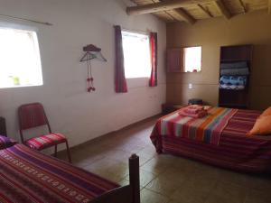 - une chambre avec deux lits, une chaise et deux fenêtres dans l'établissement Cabaña El Cardón,casita en el campo quebradeño, à Humahuaca