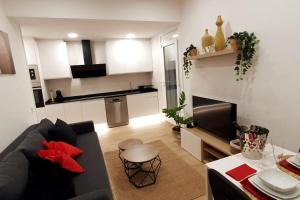 sala de estar con sofá negro y cocina en Preciosa casa reformada a 20 min de Barcelona, en Cabrils