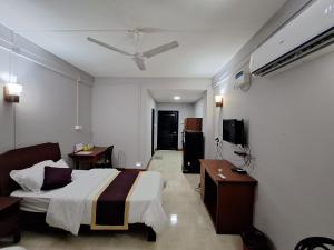 ein Hotelzimmer mit einem Bett und einem TV in der Unterkunft Hotel Chhungte International in Aizawl