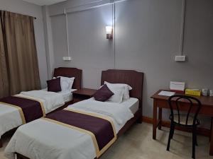 una camera d'albergo con 2 letti e una scrivania di Hotel Chhungte International ad Āīzawl
