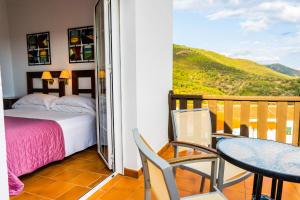 a bedroom with a bed and a balcony with a table and chairs at Complejo Los Veneros in Santa Ana la Real