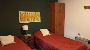 a bedroom with two beds and a painting on the wall at La Pirca Rosada in San Fernando del Valle de Catamarca