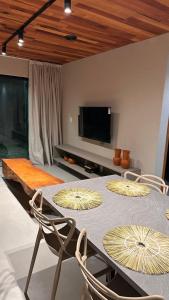 a dining room with a table with chairs and a tv at Vila Piá in Piaçabuçu