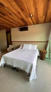 a bedroom with a white bed with a wooden ceiling at Vila Piá in Piaçabuçu