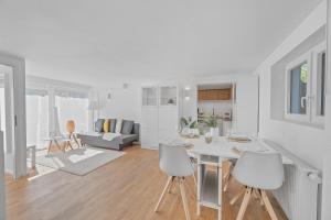 eine weiße Küche und ein Wohnzimmer mit einem Tisch und Stühlen in der Unterkunft FEEL HOME Apartments in Schönaich