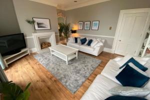 a living room with a white couch and a tv at Waimea House Beach Front The best sea views in Scarborough