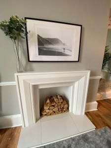 a white fireplace with a pile of fire wood at Waimea House Beach Front The best sea views in Scarborough