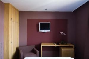 1 dormitorio con pared morada, escritorio y TV en Pol Hotel, en Le Touquet-Paris-Plage