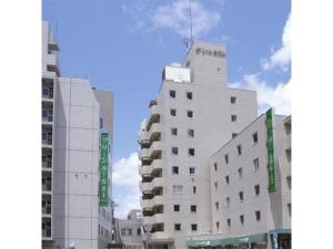 Green Hotel Kitakami - Vacation STAY 09840v في كيتاكامي: مبنى أبيض طويل مع ساعة عليه