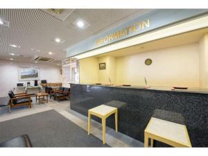 Green Hotel Kitakami - Vacation STAY 09840v في كيتاكامي: غرفة انتظار مع طاولات وكاونتر مع علامة الافينيشن